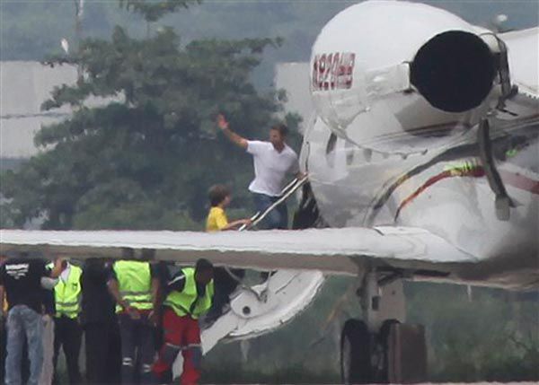 Photograph of David Goldman waving as he and son David (in yellow shirt) board a plane in Rio.